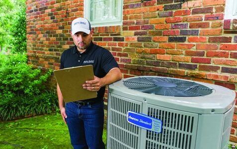 HVAC technician leaning against air conditioner